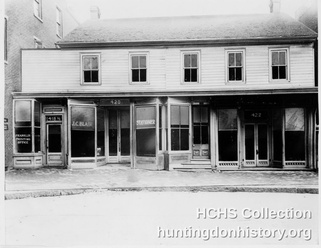 Black-and-white 1878 photograph of J.C. Blair's original store at 418-422 Penn Street in Huntingdon, Pennsylvania, with 'J.C. Blair' and 'Stationer' lettered on the storefront windows.